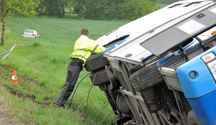 Převrácený autobus, v pozadí osobní auto, jehož řidič včas uhnul do pole