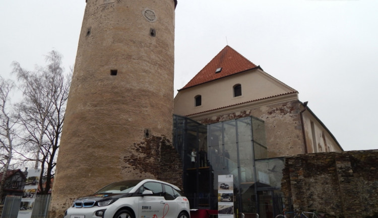 BMW i3 a v pozadí gotický hrad, ve kterém se nachází moderní městská knihovna