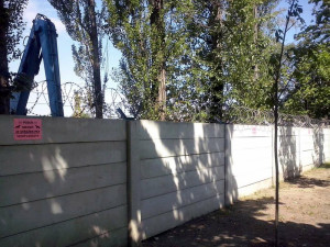 Oplocený pozemek kovošrotu. V létě tam byly doplněny upozornění, že je objekt střežen psy