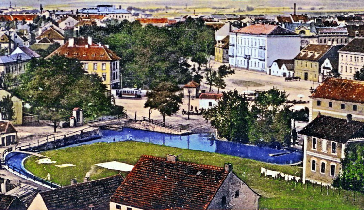 Senovážné náměstí s vodními rameny Mlýnské stoky, které vytváří ostrov, stromovím, tramvají a starou nemocnicí kolem roku 1912