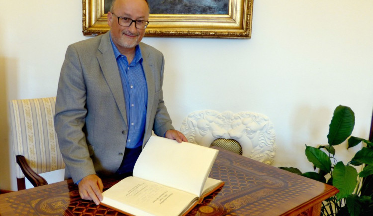 Primátor Jiří Svoboda listuje pamětní knihou.