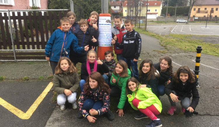 Děti vylepují plakát, který upozorňuje na jejich akci.