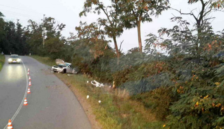 Opilý řidič poslal auto do stromu, spolujezdec vylétl dveřmi a zůstal zaklíněný pod autem