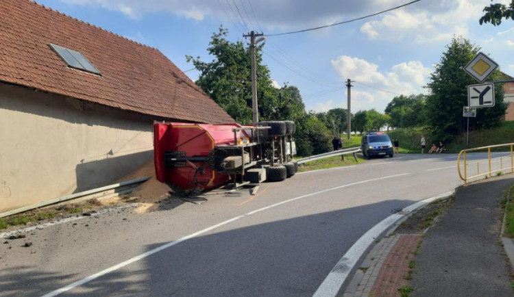 Mladý traktorista nezvládl průjezd zatáčkou, na dům a silnici vysypal 16 tun pšenice