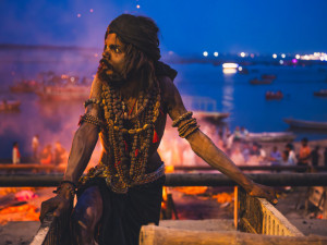 Aghori a za ním hořící kremační oheň ve Varansí