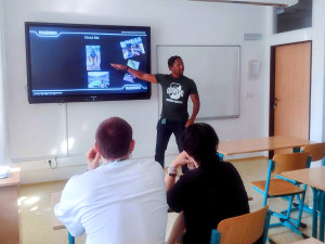 Americký asistent Issac Mcgee se představuje žákům na Střední škole obchodní.