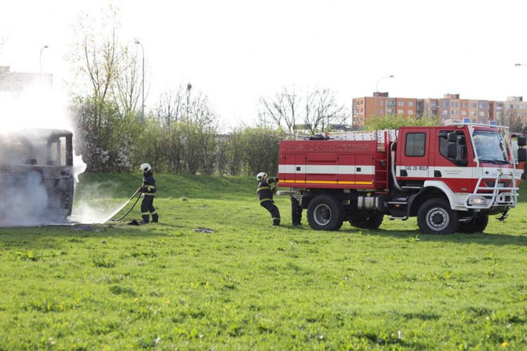 Požár vraku autobusu na louce u Vltavy v Českých Budějovicích