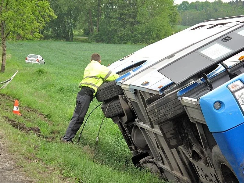 Převrácený autobus, v pozadí osobní auto, jehož řidič včas uhnul do pole