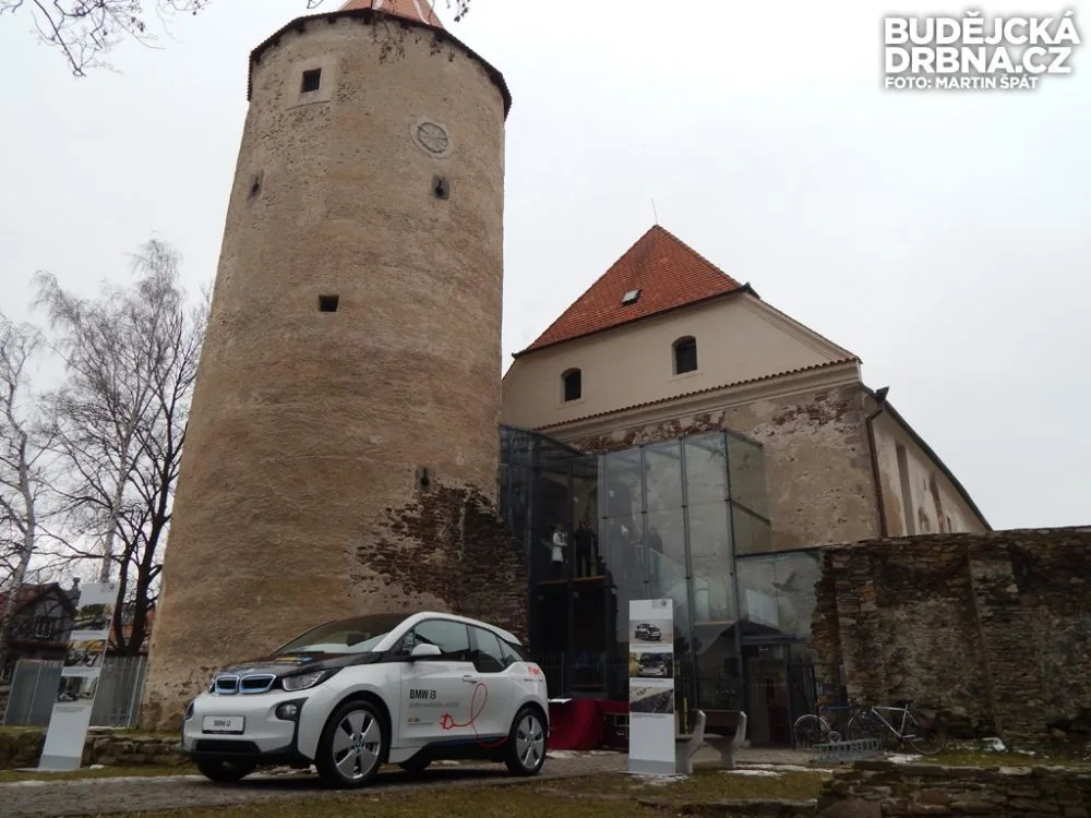 BMW i3 a v pozadí gotický hrad, ve kterém se nachází moderní městská knihovna