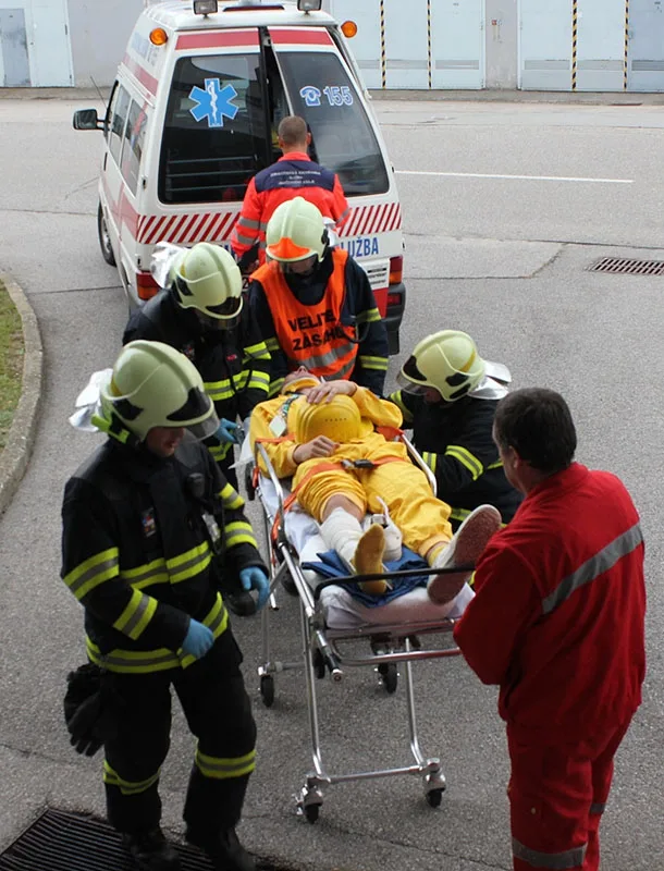 Hasiči odnášejí zraněného pracovníka k dozimetrické kontrole