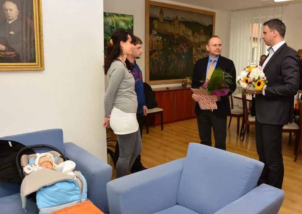Hejtman Jiří Zimola a starosta Sezimova Ústí Martin Doležal se chystají předat dary manželům Aleně a Petrovi Holušovým. Malý Vojta přitom klidně spí pod obrazem Edvarda Beneše
