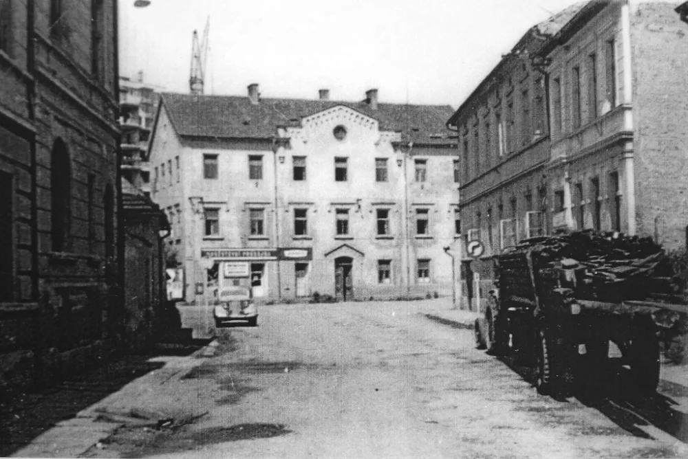 Staroměstská ulice se staroměstskou školou před rokem 1970. Zezadu se agresivně tlačí na školu panelák.
