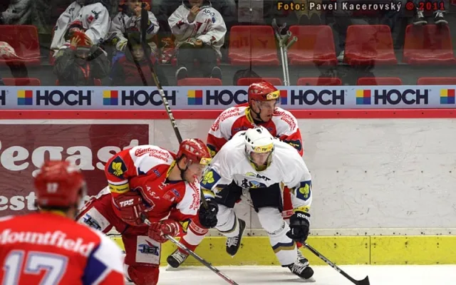 U mantinelu bojují s Jiřím Kuchlerem domácí forvardi Roman Pšurný (v pokleku) a Tomáš Mertl