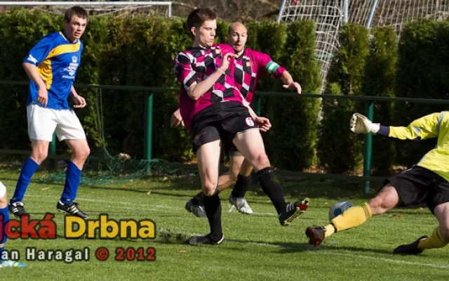 Karel Voldán (zcela vlevo) střílí jedinou branku utkání Hluboká - Jindřichův Hradec. Janeček i brankář Brašnička byli na jeho střelu krátcí