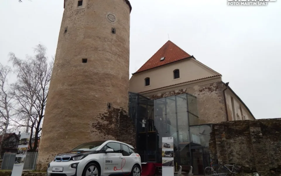 BMW i3 a v pozadí gotický hrad, ve kterém se nachází moderní městská knihovna