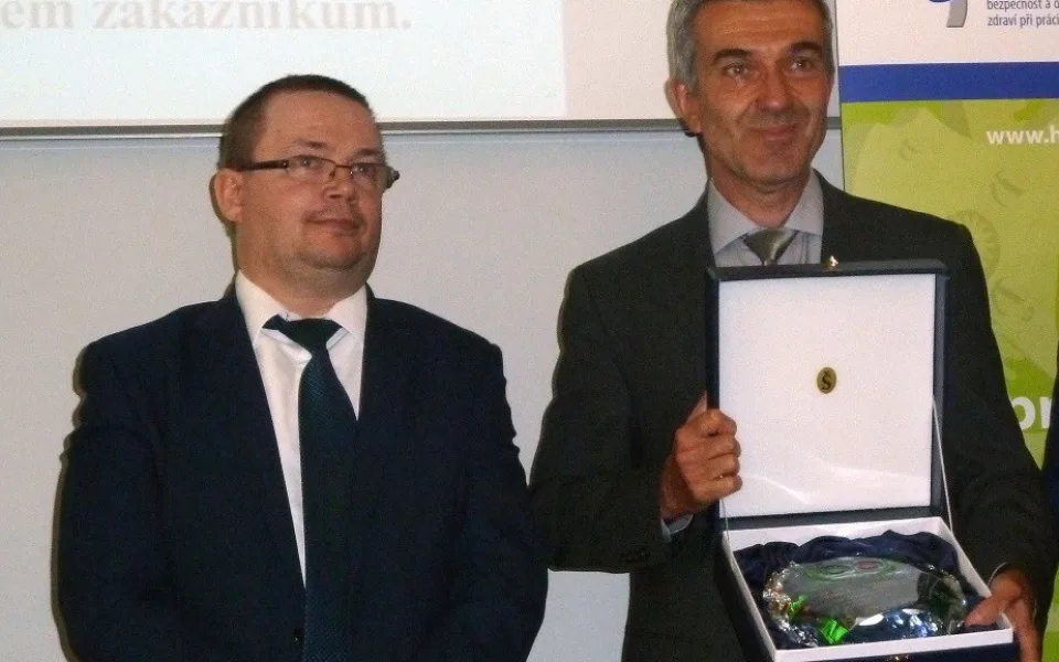 Miroslav Houfek s oceněním Bezpečný podnik, které mu předal vedle stojící Jiří Vaňásek, náměstek ministryně práce a sociálních věcí