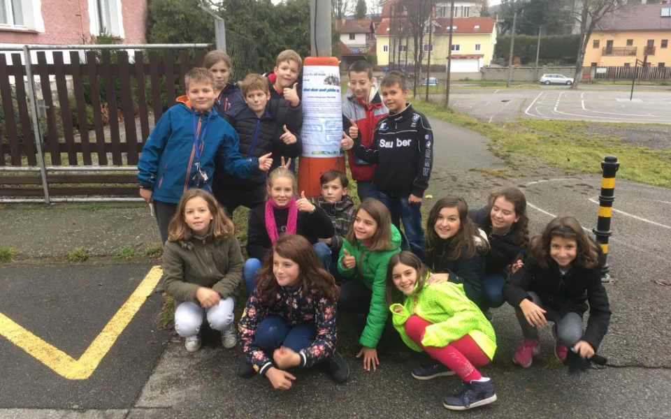Děti vylepují plakát, který upozorňuje na jejich akci.
