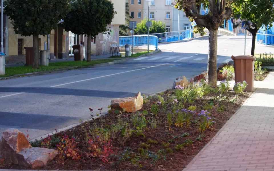 Dříve na travnaté ploše parkovala auta. Dnes je tam místo parkoviště květinový záhon