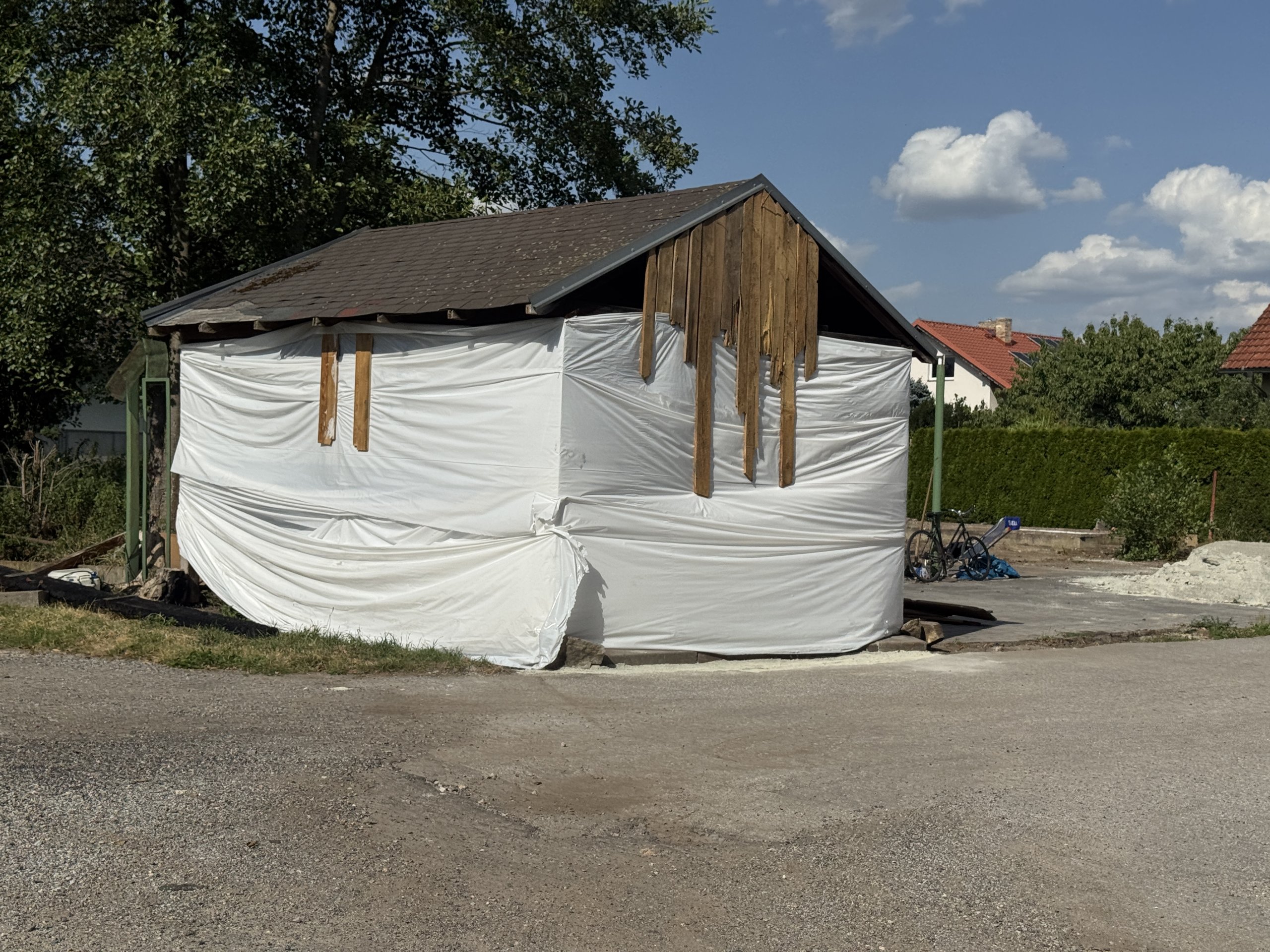 Prodal vilu a teď squattuje na sousedním pozemku. Z přístřešku si buduje provizorní bydlení
